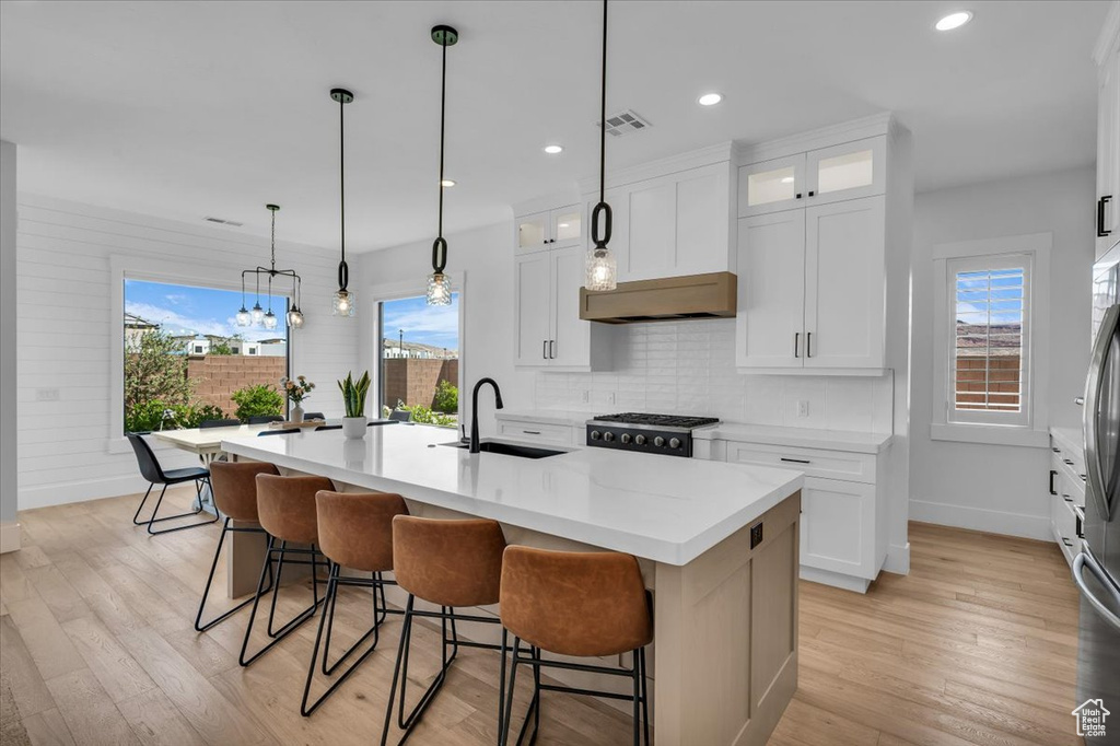 Kitchen featuring tasteful backsplash, healthy amount of natural light, light countertops, recessed lighting, and a kitchen island with sink