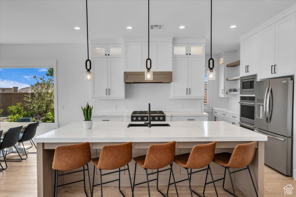 Kitchen featuring appliances with stainless steel finishes, recessed lighting, open shelves, white cabinets, and light wood-style flooring