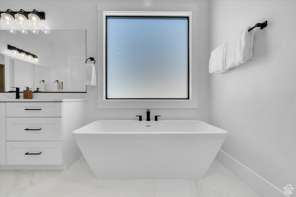 Full bathroom with vanity, a freestanding tub, and marble look tile flooring