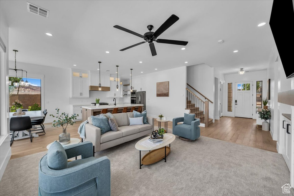 Living area with light wood-type flooring, healthy amount of natural light, stairway, and recessed lighting