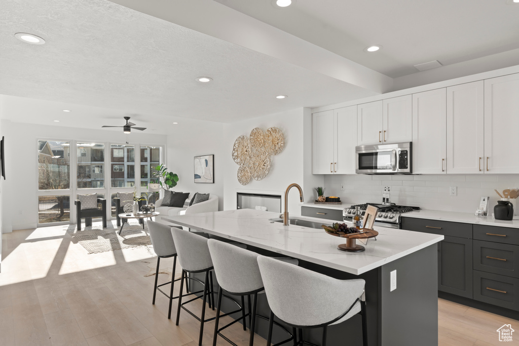 Kitchen with stainless steel microwave, tasteful backsplash, a breakfast bar, recessed lighting, and range