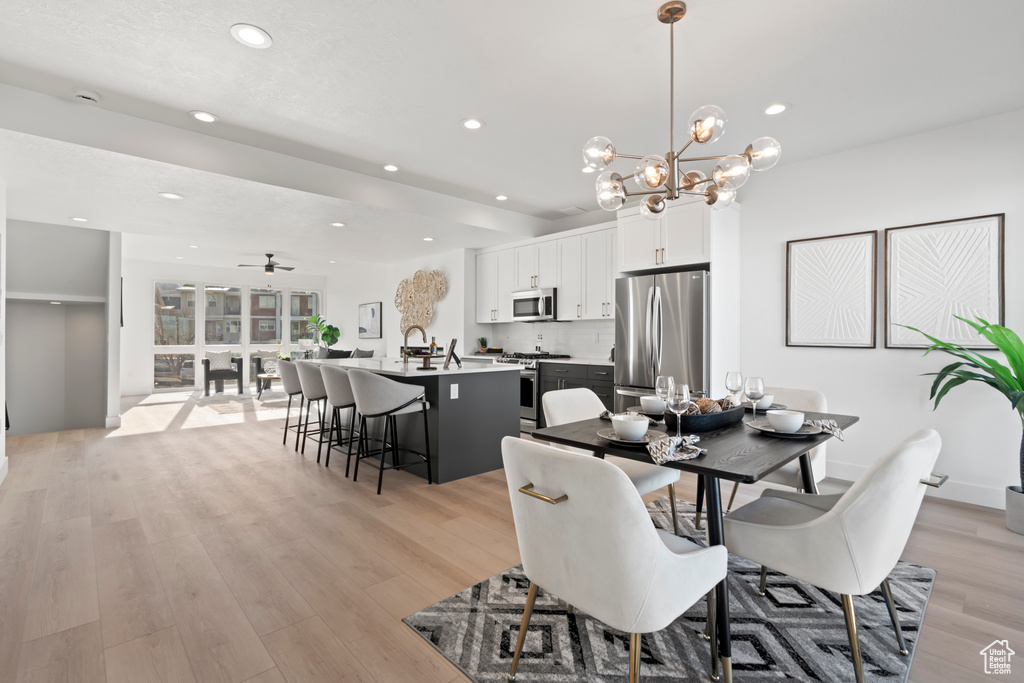 Dining room with light wood-style floors, a chandelier, recessed lighting, and a ceiling fan