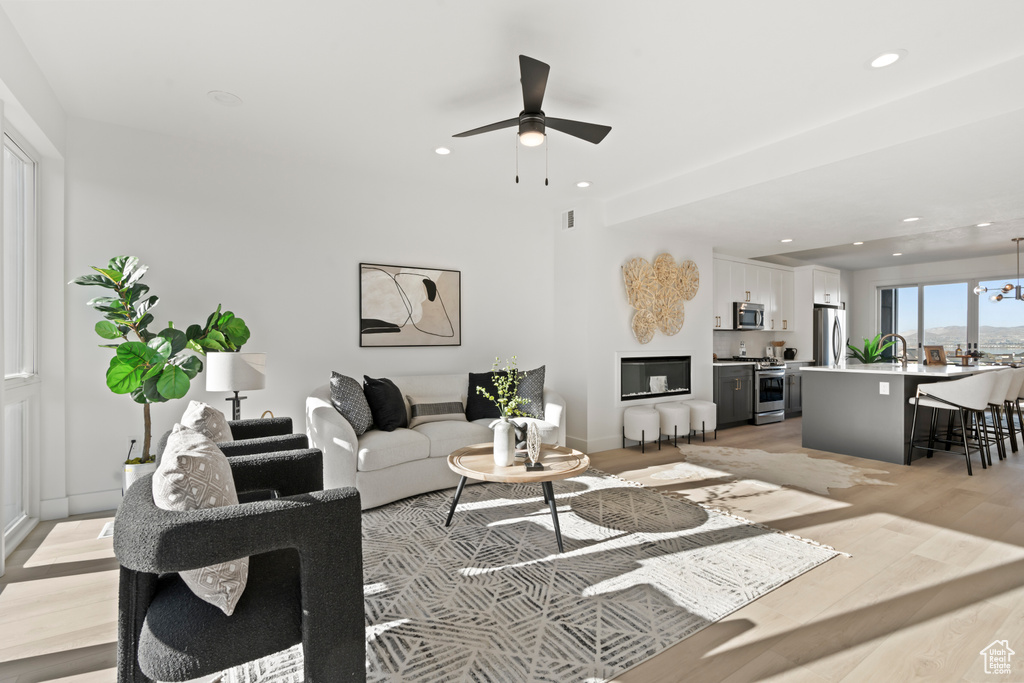 Living area with light wood finished floors, ceiling fan, and recessed lighting