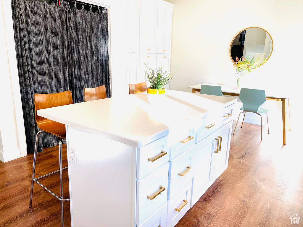 Kitchen with a breakfast bar, light wood-style floors, a kitchen island, and white cabinets