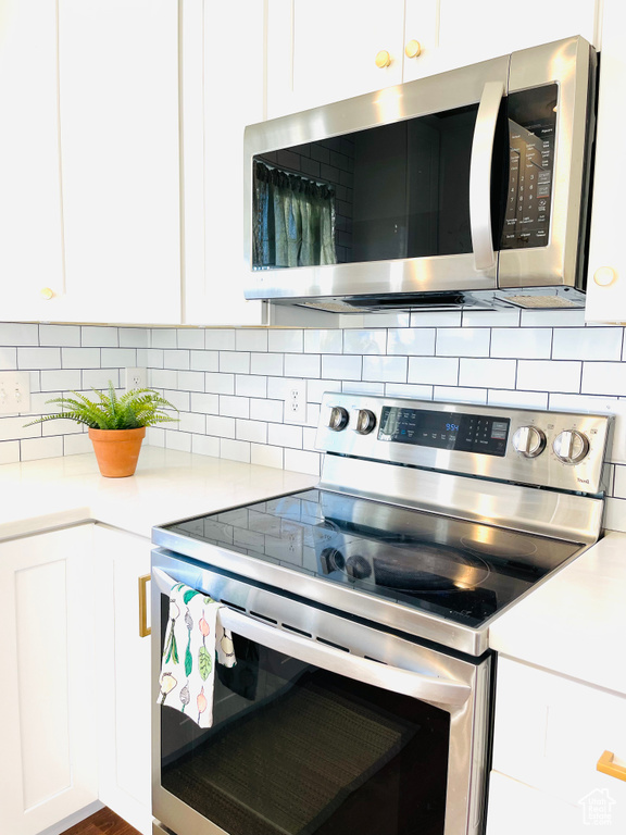 Kitchen featuring appliances with stainless steel finishes, white cabinetry, and light countertops