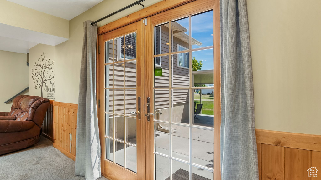 Doorway to outside featuring a wainscoted wall, carpet, and wooden walls