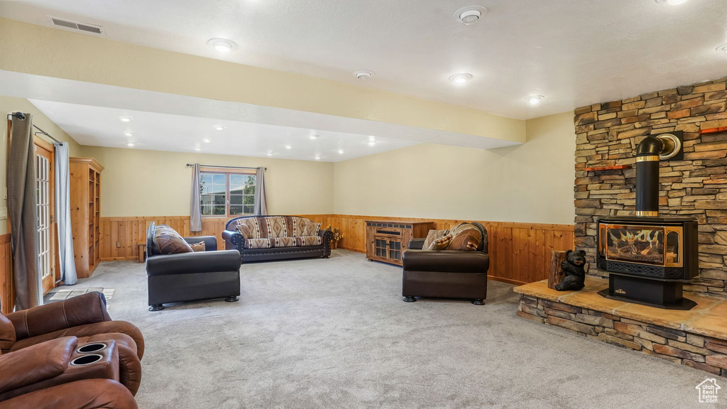 Living room with a wainscoted wall, wood walls, a wood stove, carpet flooring, and recessed lighting