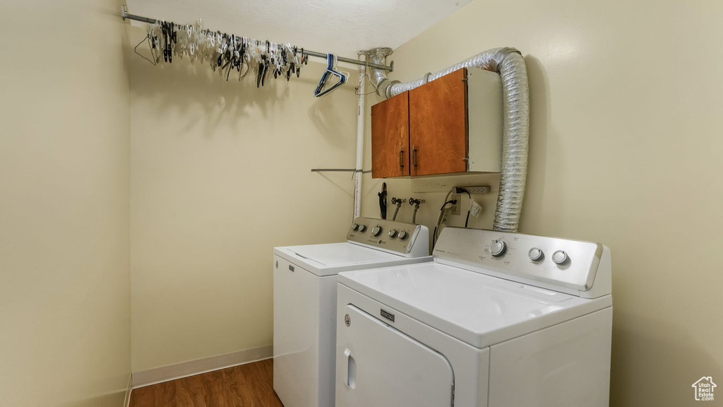 Laundry area featuring cabinet space, washer and dryer, and wood finished floors