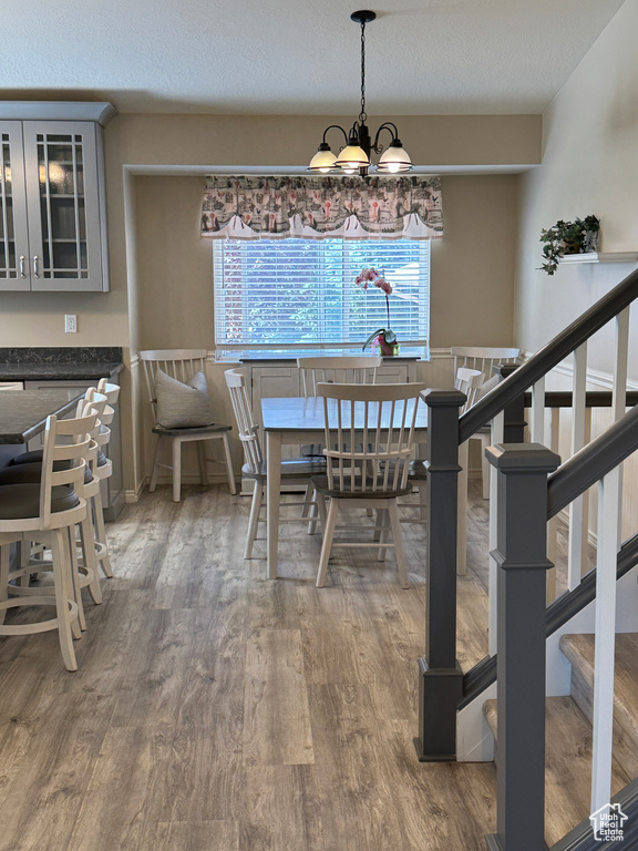 Dining area featuring stairway, wood finished floors, a chandelier, and a textured ceiling