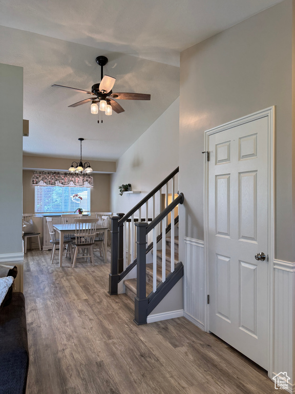 Stairs with wood finished floors, a chandelier, and a ceiling fan