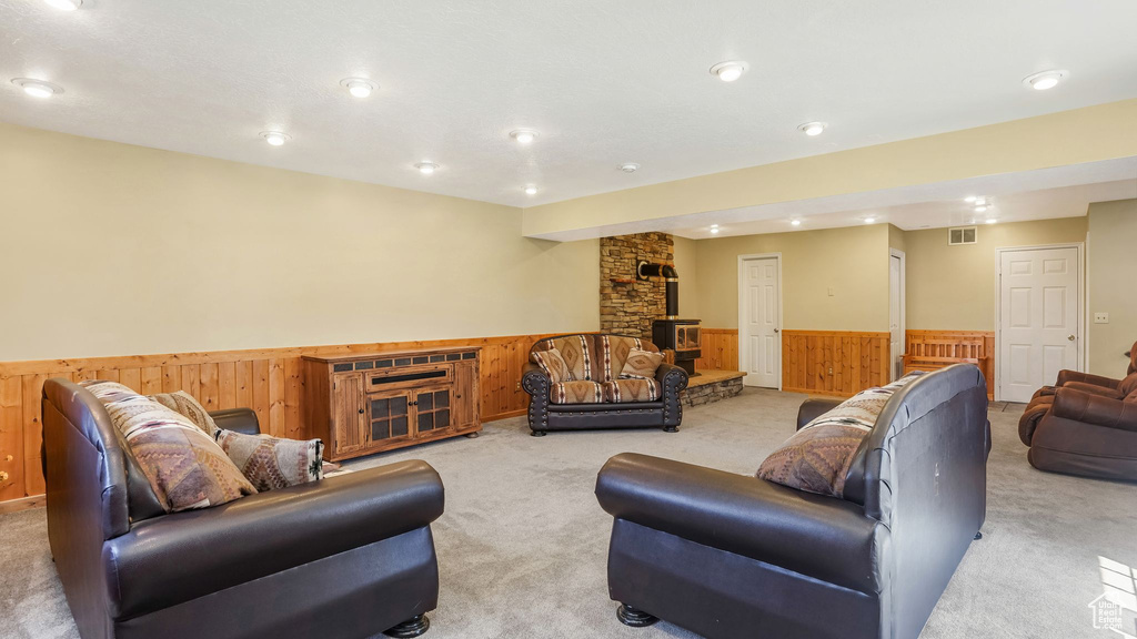 Carpeted living area featuring a wainscoted wall, wooden walls, recessed lighting, and a wood stove