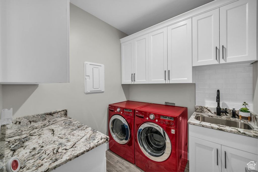 Washroom with cabinet space, washer and clothes dryer, and light wood finished floors