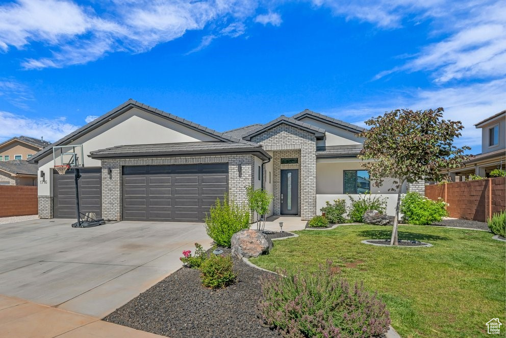 Ranch-style house featuring concrete driveway, an attached garage, brick siding, and stucco siding
