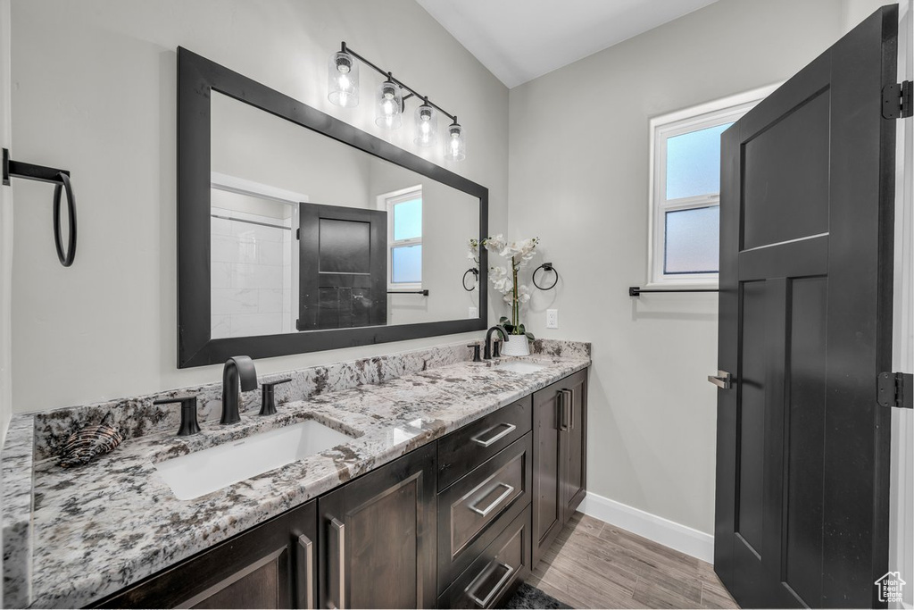 Full bathroom with double vanity, plenty of natural light, and wood finished floors