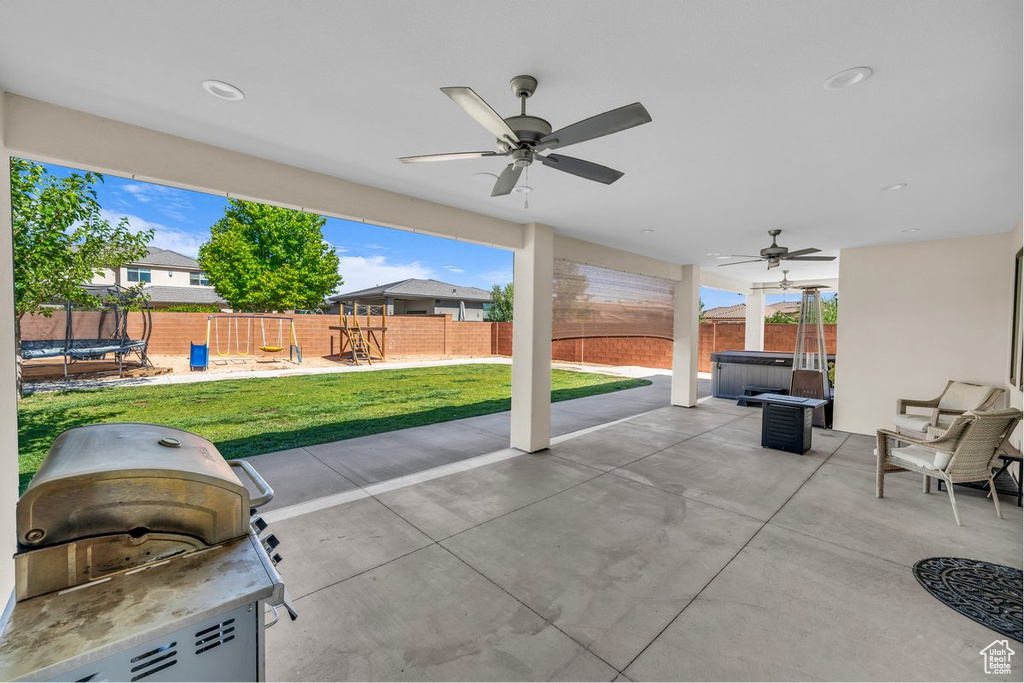 Fenced backyard featuring a trampoline, ceiling fan, a playground, a patio area, and a grill