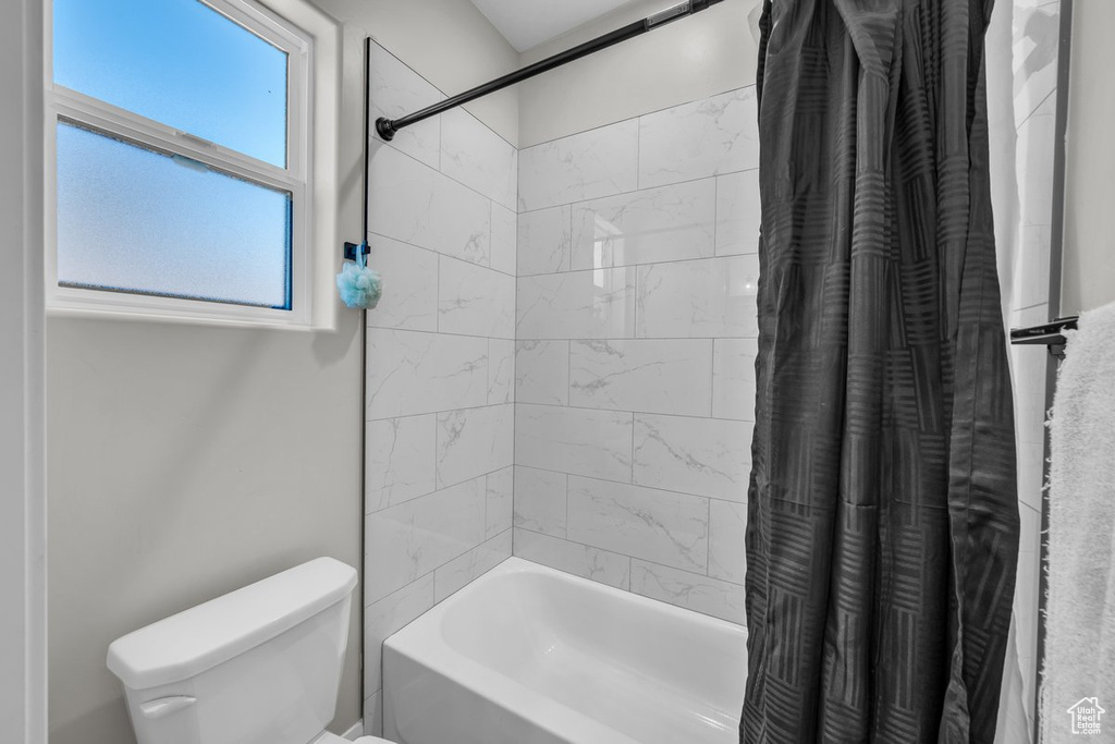 Bathroom with shower / bathtub combination with curtain and toilet