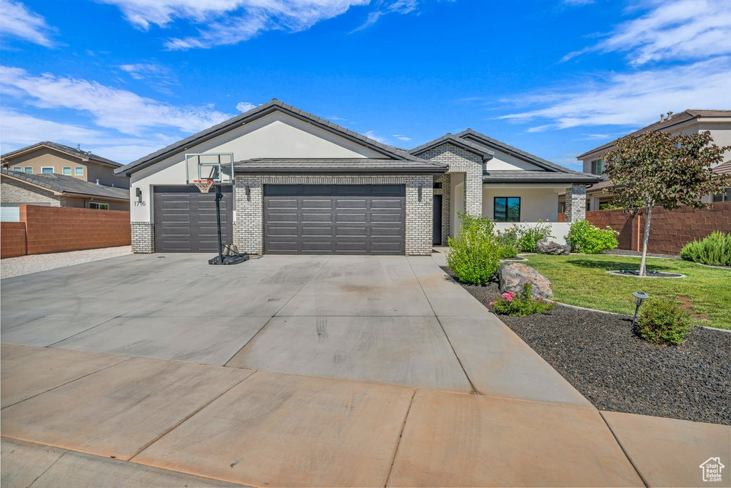 Ranch-style house featuring an attached garage, concrete driveway, brick siding, and stucco siding