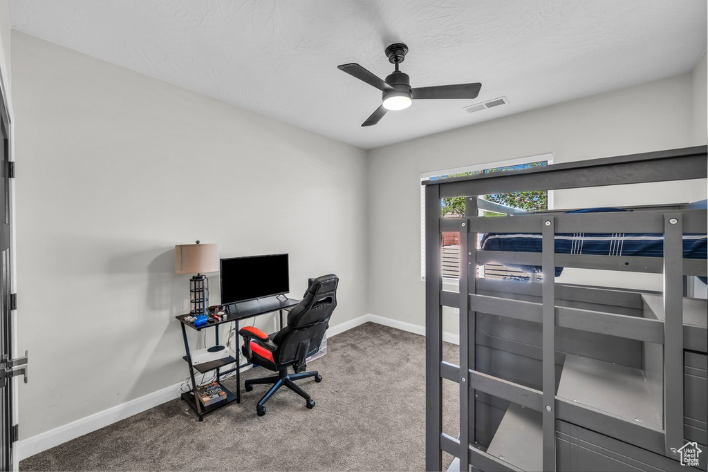 Bedroom with carpet floors, a desk, and a ceiling fan