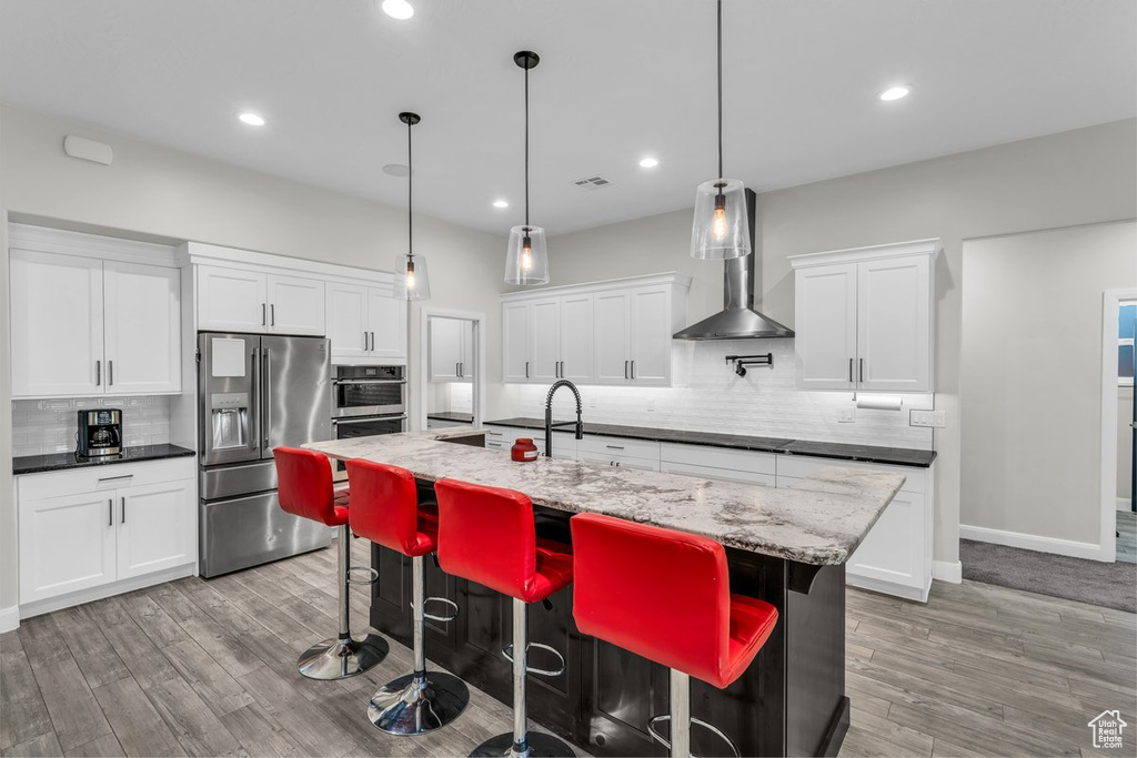 Kitchen with stainless steel appliances, decorative backsplash, light wood-type flooring, and recessed lighting