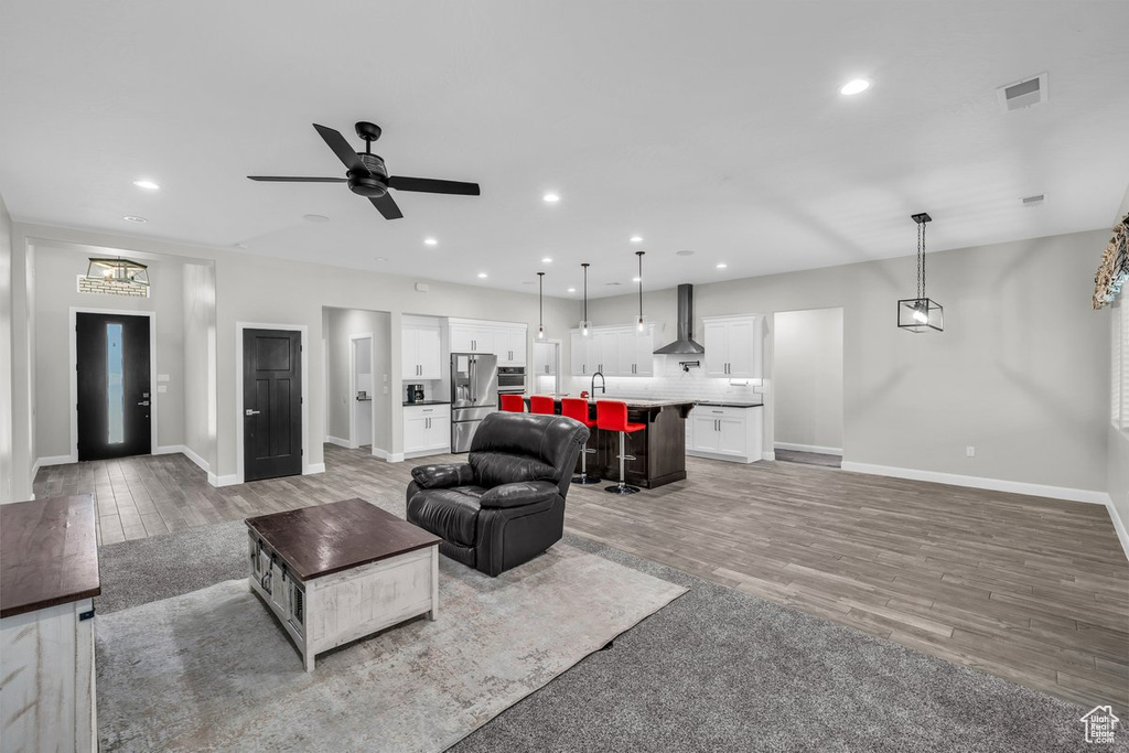 Living room with light wood finished floors, ceiling fan, and recessed lighting