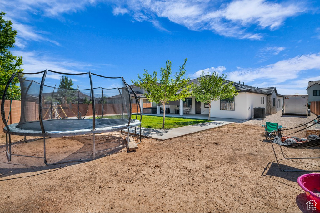 View of yard featuring a trampoline and a patio