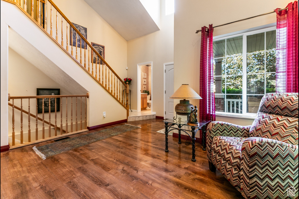 Living area with wood finished floors, a towering ceiling, and stairs