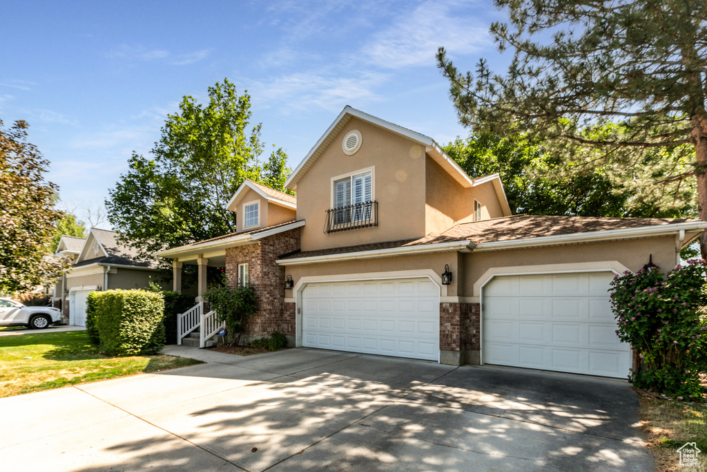 Traditional-style house featuring driveway, stucco siding, brick siding, and a garage