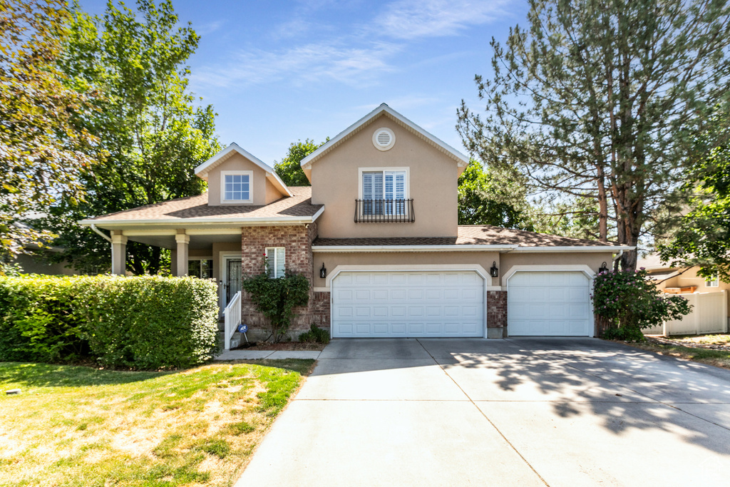 View of front of property featuring concrete driveway, stucco siding, an attached garage, a shingled roof, and a front lawn