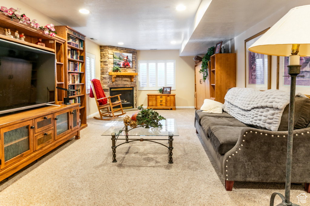 Carpeted living area featuring a stone fireplace and recessed lighting