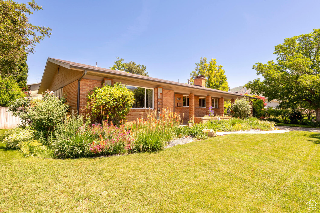 Ranch-style house with brick siding, a chimney, and a front yard