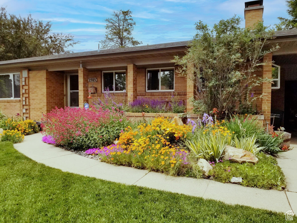 View of front facade featuring brick siding, a chimney, and a front lawn