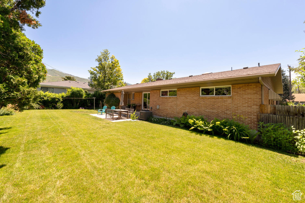 Back of house with brick siding, a patio, and a chimney