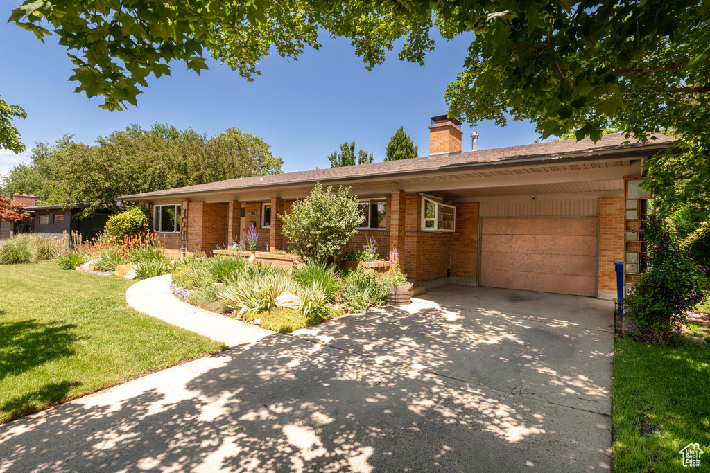 Ranch-style home with brick siding, concrete driveway, a front lawn, and an attached garage