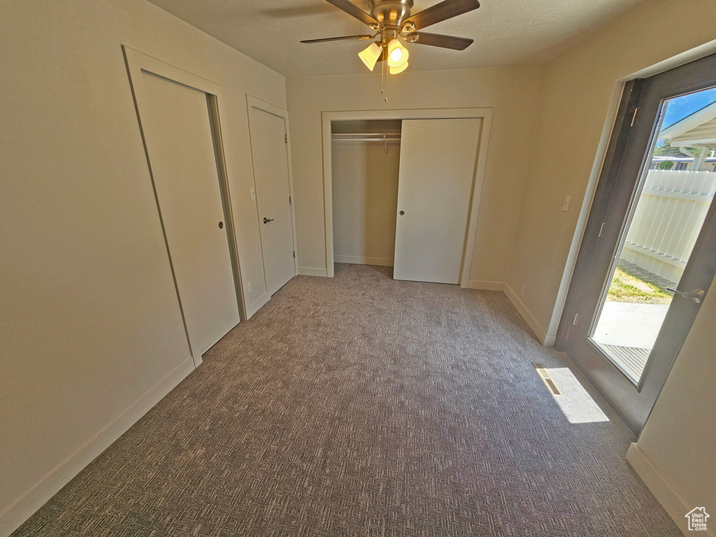 Unfurnished bedroom with carpet flooring, multiple closets, and a ceiling fan