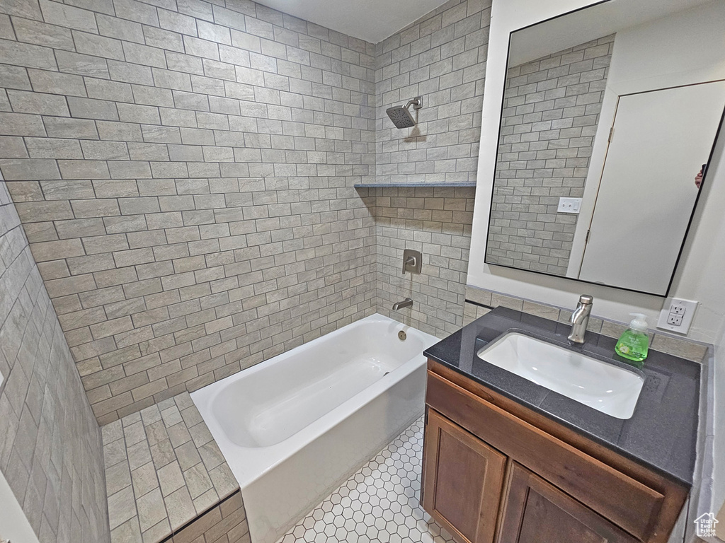 Full bath featuring tile walls, vanity, and washtub / shower combination
