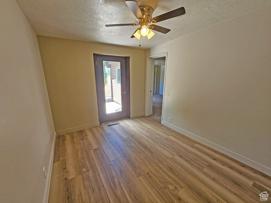 Spare room with wood finished floors, a textured ceiling, and a ceiling fan