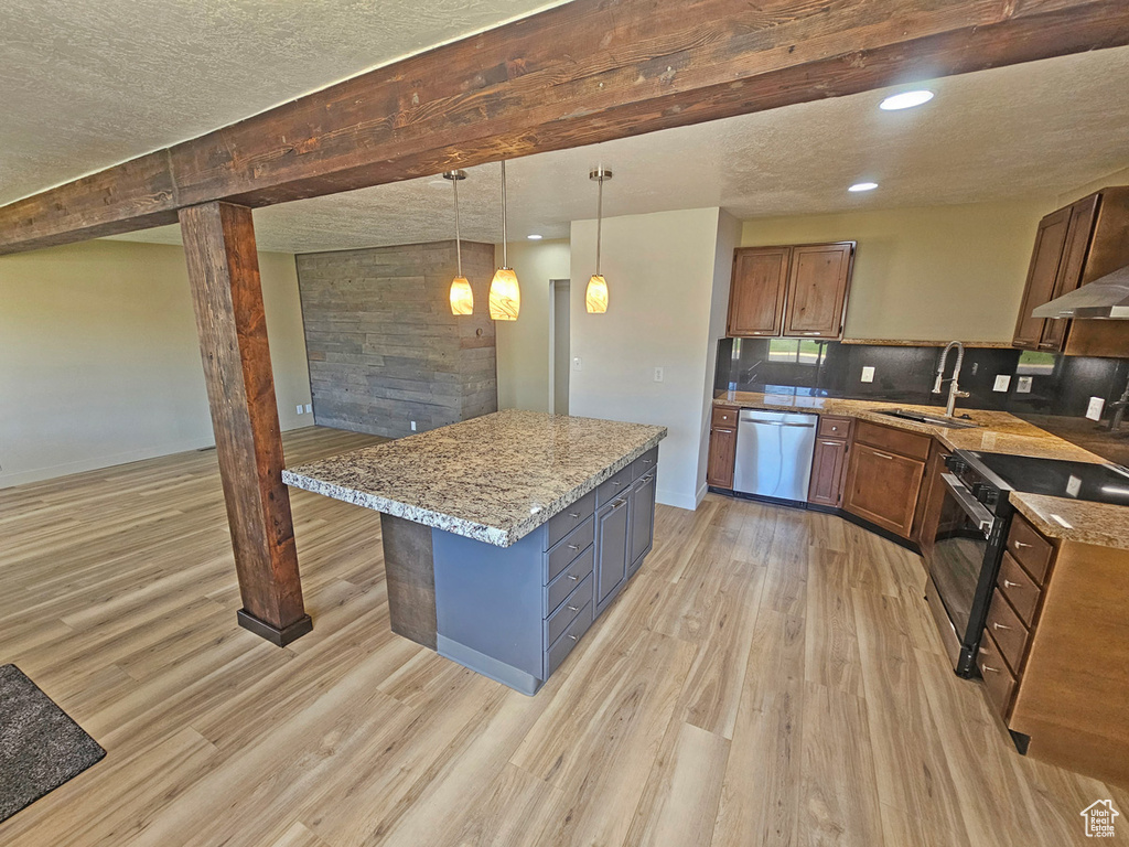 Kitchen featuring appliances with stainless steel finishes, light wood finished floors, a kitchen island, pendant lighting, and a textured ceiling
