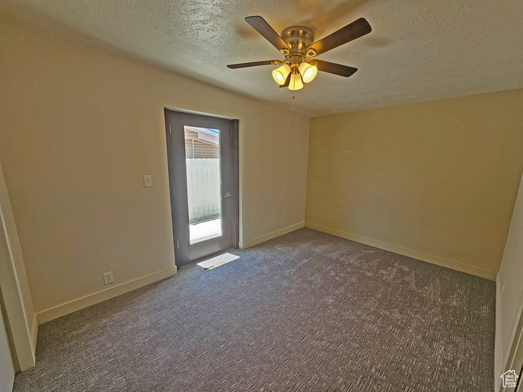 Carpeted spare room with a textured ceiling and a ceiling fan