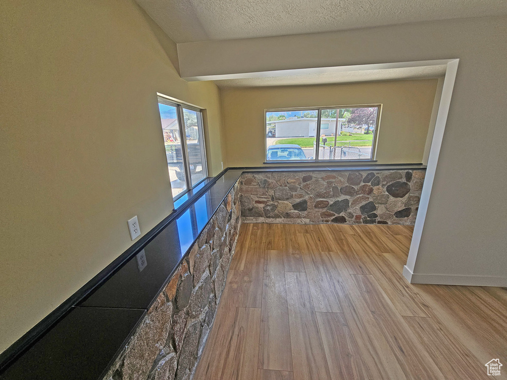 Spare room featuring wood finished floors, healthy amount of natural light, and a textured ceiling