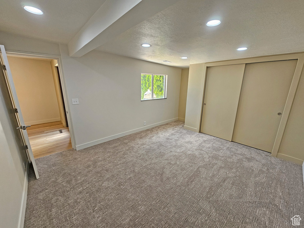 Unfurnished bedroom with light colored carpet, recessed lighting, a textured ceiling, and a closet