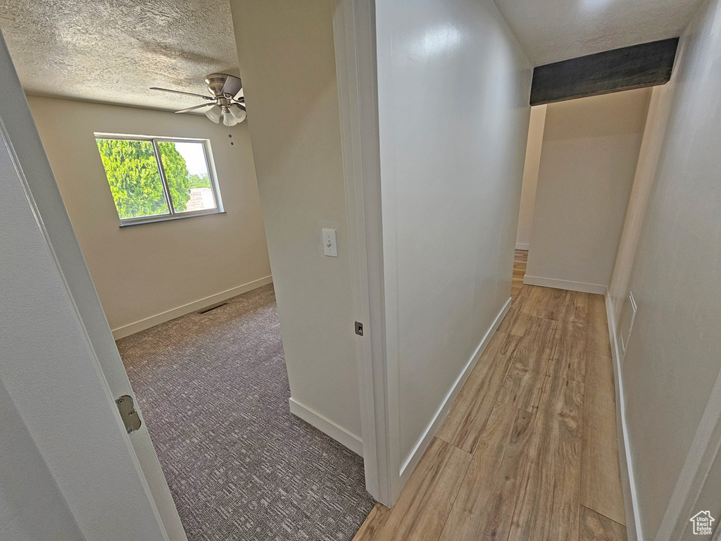 Hall featuring a textured ceiling and wood finished floors