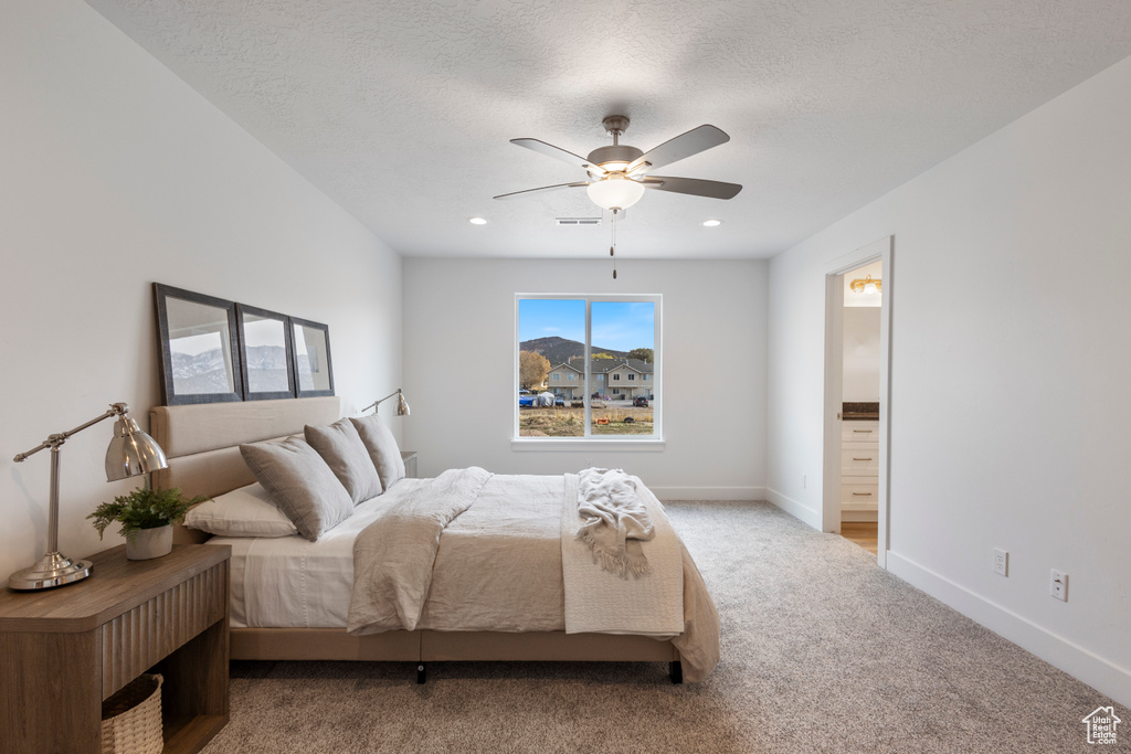 Carpeted bedroom with ensuite bath, a ceiling fan, and a textured ceiling