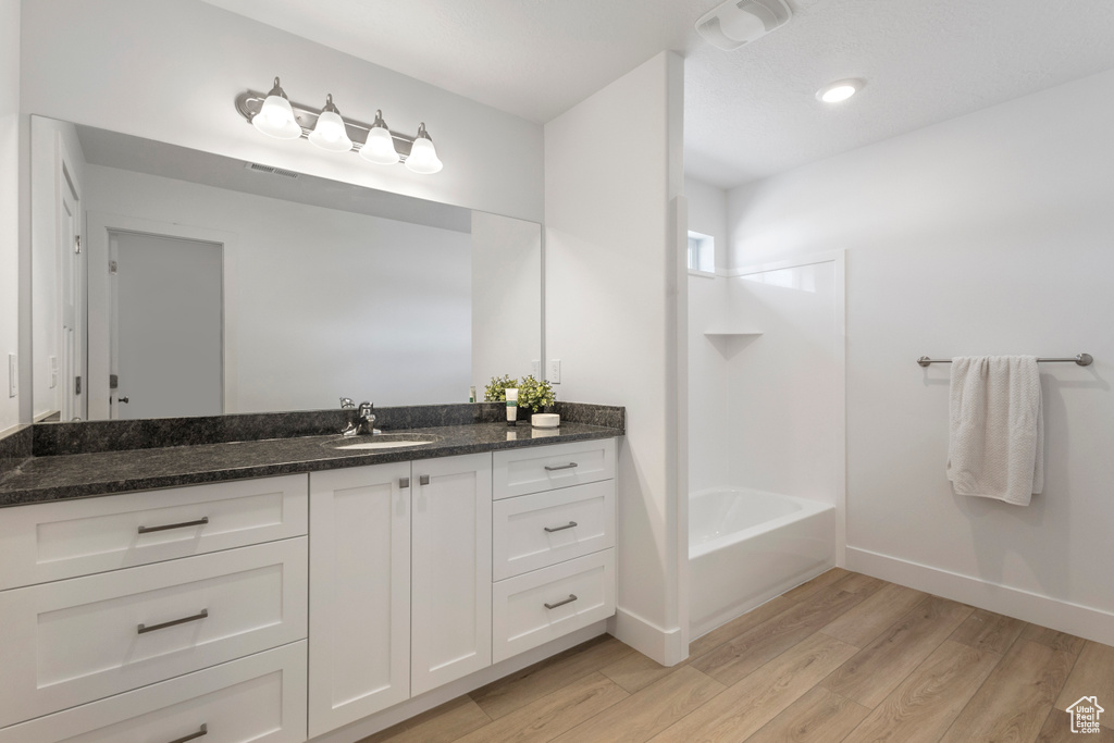 Full bath with wood finished floors, vanity, and shower / bath combination