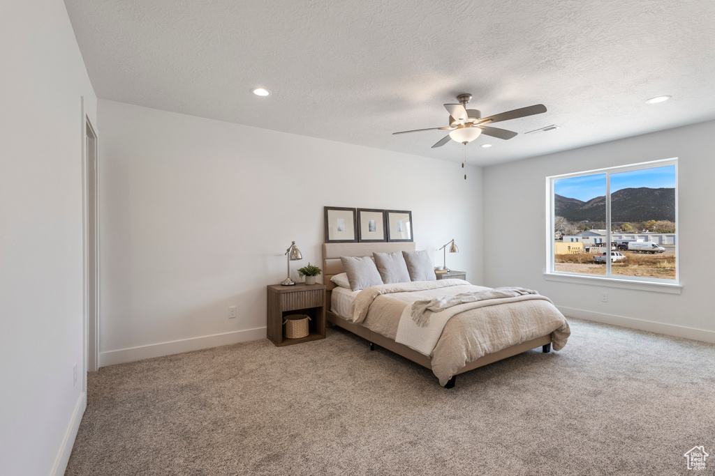 Carpeted bedroom with a textured ceiling, recessed lighting, a ceiling fan, and a mountain view