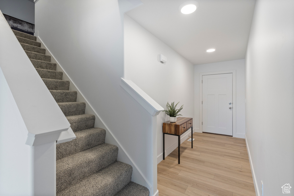 Stairway featuring wood finished floors and recessed lighting