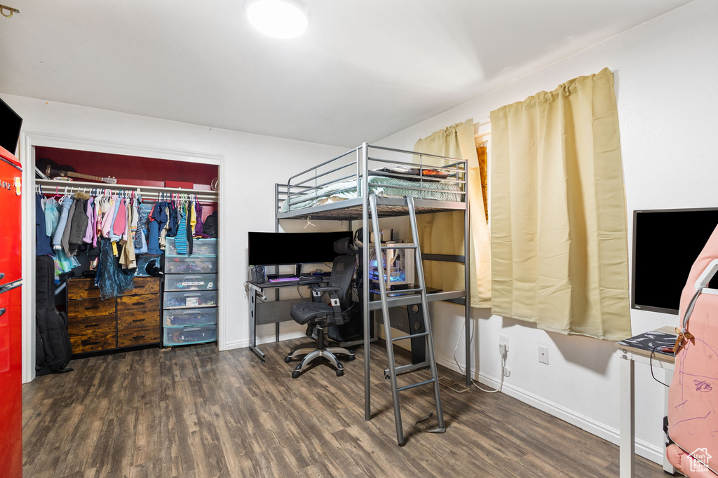 Bedroom with wood finished floors, a desk, and a closet