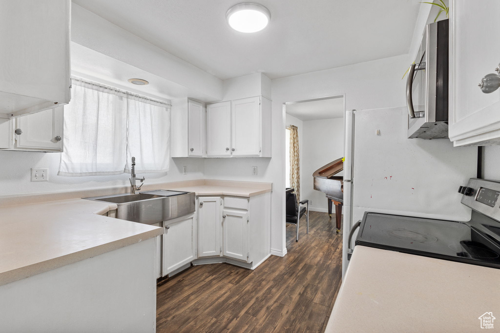 Kitchen featuring stainless steel appliances, white cabinetry, dark wood-type flooring, and light countertops
