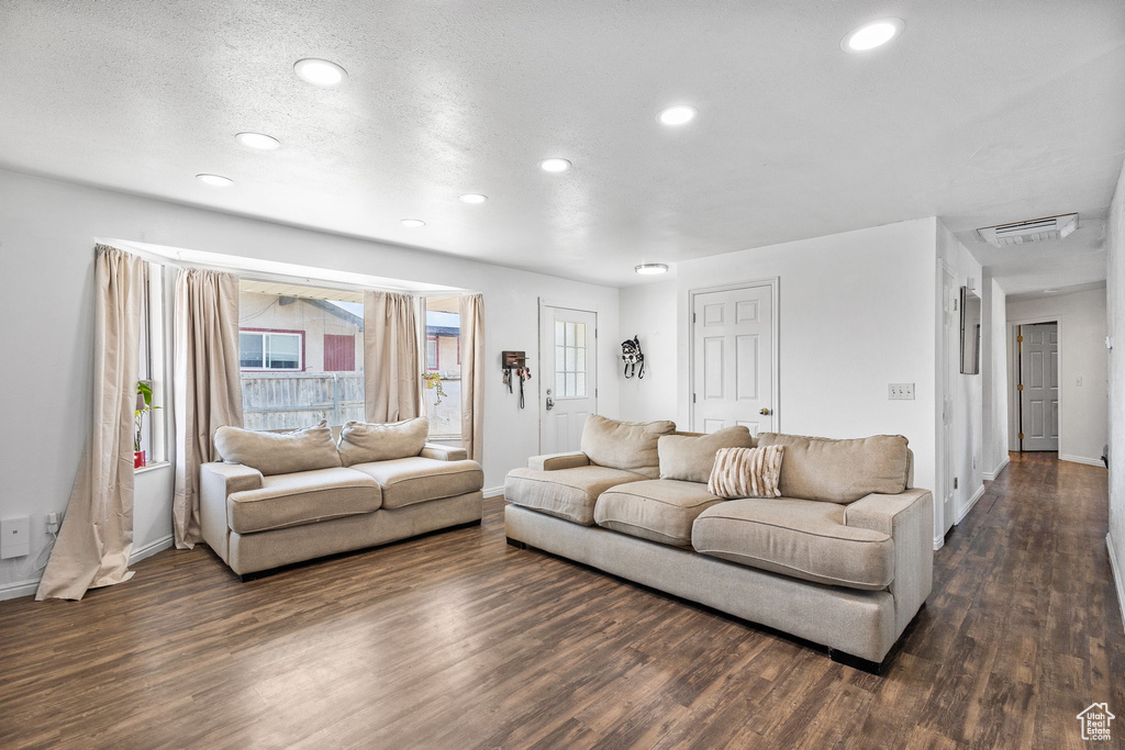 Living area with dark wood-type flooring and recessed lighting