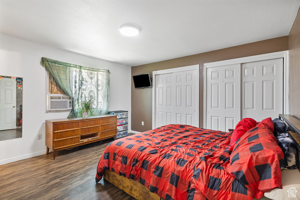 Bedroom with cooling unit, multiple closets, and wood finished floors