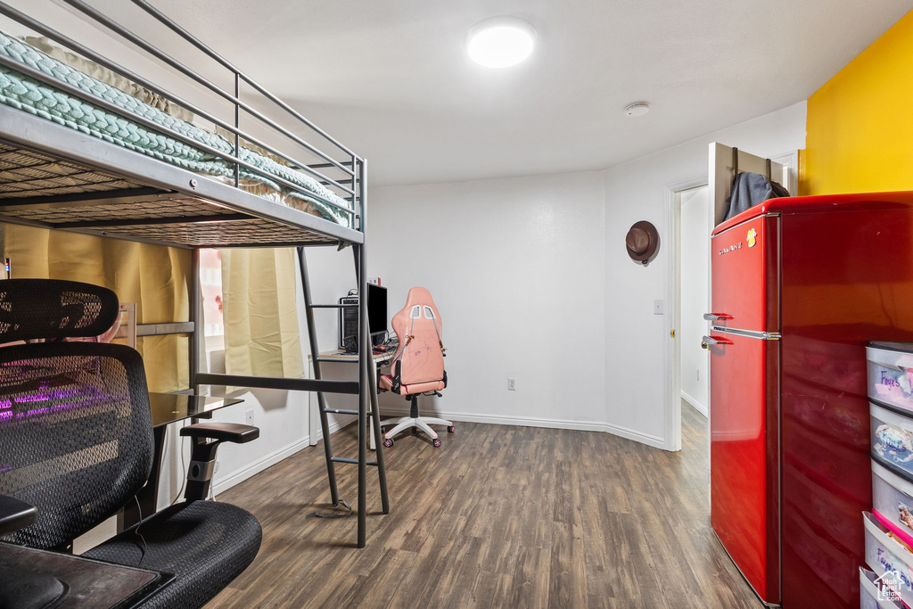 Bedroom with freestanding refrigerator and wood finished floors